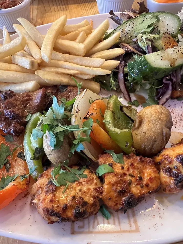 Mixed grill plate of lamb and chicken with grilled peppers, onion, mushroom, chips and salad